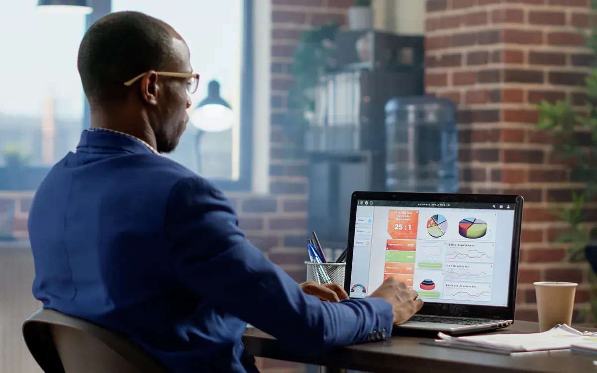 Dirigeant noir analysant un tableau de bord de performances commerciales sur son ordinateur portable