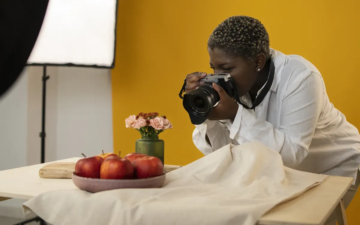 Photographe noire réalisant une séance photo culinaire en studio, devant un fond jaune